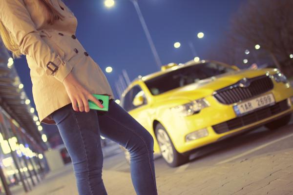 čakajúca žena pred žltým taxi