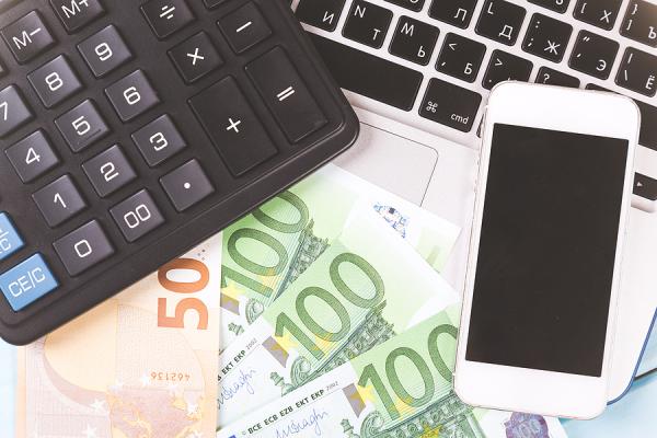 peniaze, kalkulačka, mobil a notebook na stole