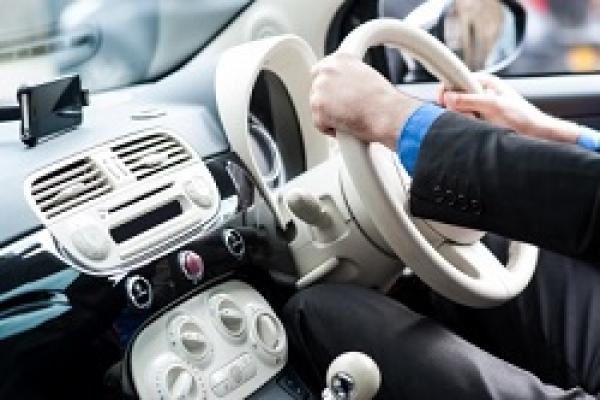 človek sediaci za volantom auta